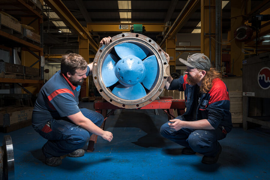 2 male SPP Pumps Service engineers with a large Kaplan turbine runner
